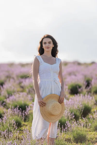 Smiling Woman White Dress Holding Straw Hat Looking Camera Lavender — ストック写真