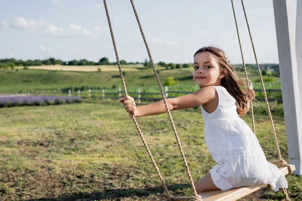 Girl Summer Dress Looking Camera While Riding Swing Field — Stock Fotó