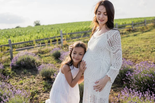 Smiling Kid Embracing Pregnant Mom While Standing Blurred Meadow — Foto de Stock