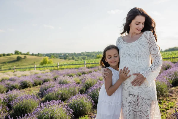 Happy Girl Embracing Tummy Pregnant Mother Blooming Lavender Field — Stock fotografie