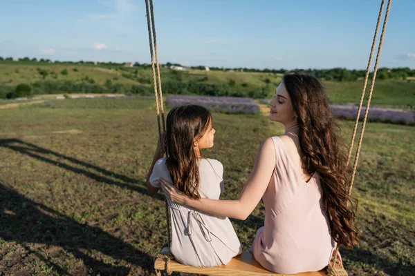 Happy Brunette Woman Looking Daughter While Riding Swing Meadow — Foto de Stock