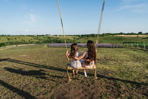 Back View Brunette Mom Daughter Riding Swing Meadow Summer Day — Stok fotoğraf