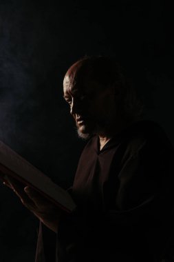 Ortaçağ keşişi karanlığın içinde kutsal İncil 'i okuyor.