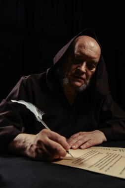 Ortaçağ rahibi, siyah üzerine izole edilmiş parşömen üzerine antik günlükler yazıyor.