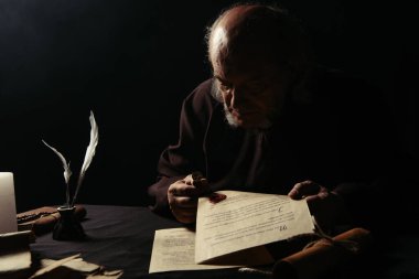 Keşiş balmumu mühür ve karanlıkta izole edilmiş el yazmaları tutuyor.