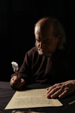 Gizemli keşiş, siyah üzerine izole edilmiş tüy kalem ile tarih yazıyor.