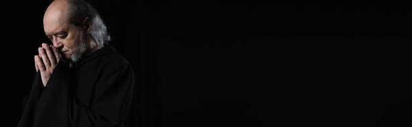 старший монах с закрытыми глазами и молитвенные руки изолированы на черном, знамя