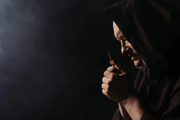 Vedere Laterală Călugărului Capotă Rugându Crucifixul Sfânt Fundal Negru — Fotografie, imagine de stoc