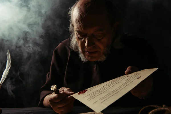 Sacerdote Sênior Olhando Selo Cera Manuscrito Fundo Escuro Com Fumaça — Fotografia de Stock
