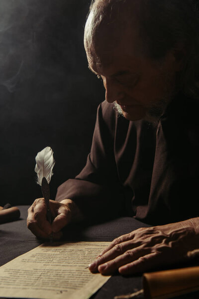 medieval chronicler writing ancient manuscript with quill pen at night on black background