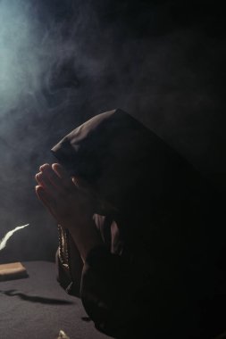 Karanlık yüzlü keşiş gece karanlığın üzerinde dumanla tespih çekiyor.
