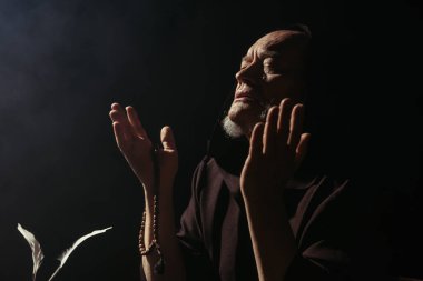 Ortaçağ rahibi siyah gözlerle ve tespihle dua ediyor.