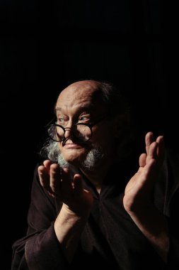 Gözlüklü düşünceli bir ortaçağ filozofu siyah bir omuz silkme hareketi sergiliyor.