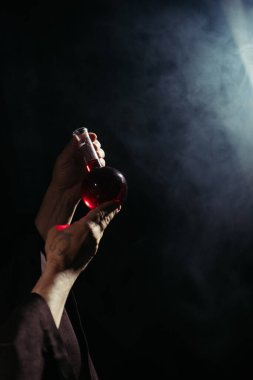 Sihirbazın elinde iksirli matarayı dumanlı siyah arka planda tutuşu