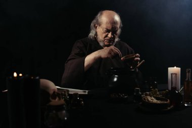 Ortaçağ simyacısı gece sihirli iksir hazırlıyor.