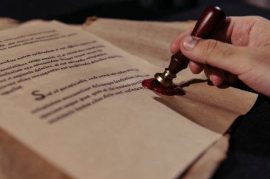 Kıdemli keşişin siyah yüzey üzerindeki balmumu mühürlü kronolojiyi onaylarken kısmi görüntüsü