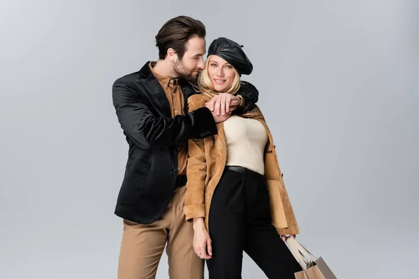 Bearded Man Hugging Happy Blonde Woman Stylish Beret Holding Shopping — Fotografia de Stock