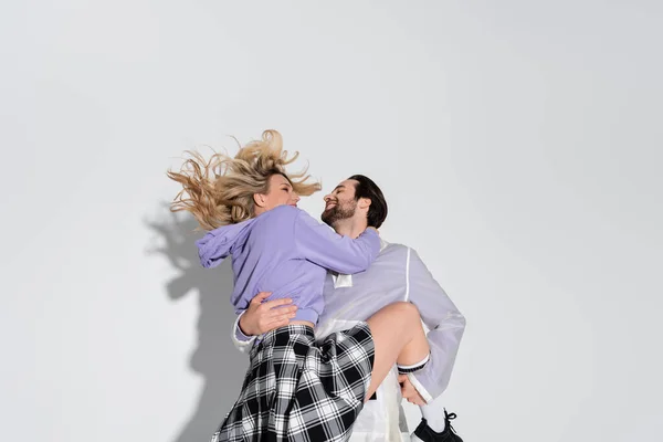 Cheerful Man Holding Arms Smiling Blonde Woman Tartan Skirt Grey — Stockfoto