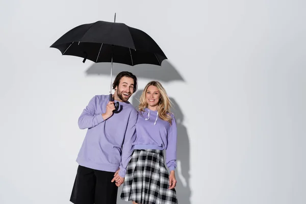 Happy Couple Purple Sweatshirts Smiling While Standing Umbrella Isolated Grey — 图库照片