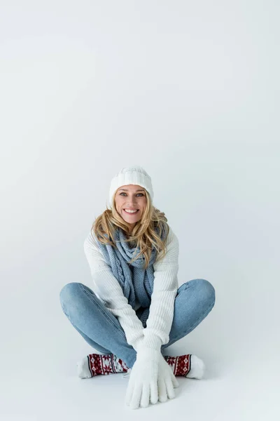Счастливая Блондинка Зимней Шляпе Вязаном Шарфе Смотрящая Камеру Сидя Сером — стоковое фото