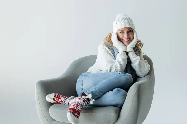 Happy Blonde Woman Winter Outfit Sitting Comfortable Armchair Isolated Grey — Stockfoto