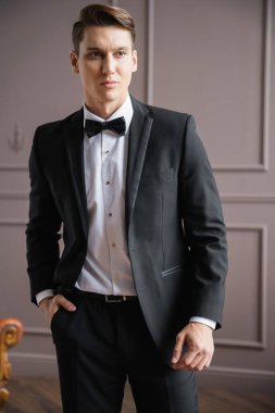 Man in suit holding hand in pocket of pants at home 