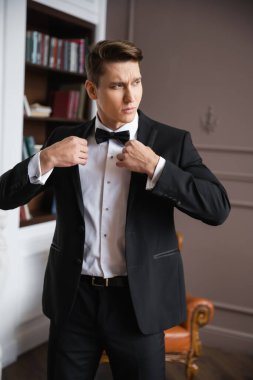 Elegant man in suit wearing jacket at home 