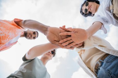 bottom view of interracial men and women joining hands