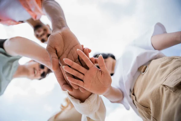 bottom view of multicultural people joining hands as sign of friendship
