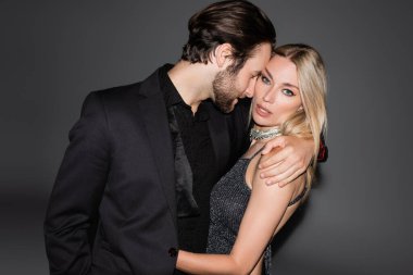 Young man in jacket hugging seductive blonde girlfriend on grey background 