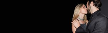 Sexy blonde woman kissing boyfriend in jacket on black background, banner 