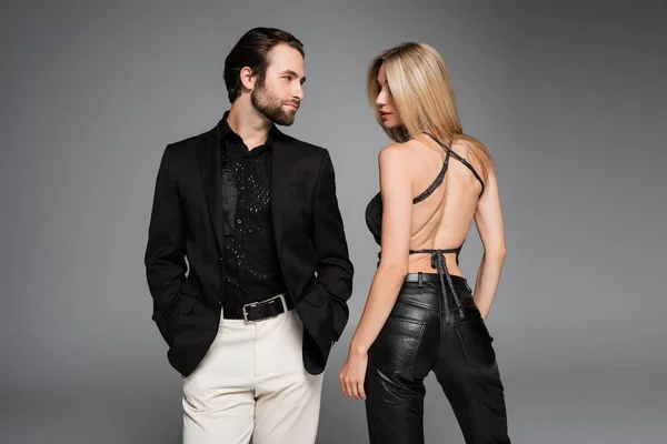 Stylish woman in leather pants standing near boyfriend isolated on grey