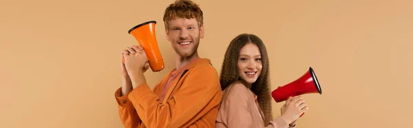 Cheerful Young Couple Holding Loudspeakers Standing Isolated Beige Banner — Stockfoto