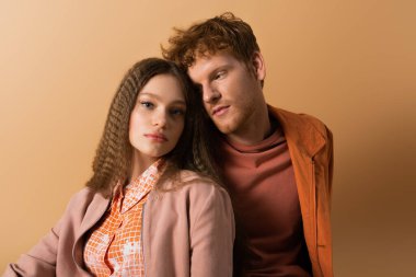 good looking young man near pretty girlfriend isolated on beige