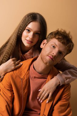 pretty girl hugging redhead and good looking boyfriend isolated on beige