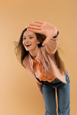 excited teenage girl in autumnal and casual clothes showing stop gesture isolated on beige