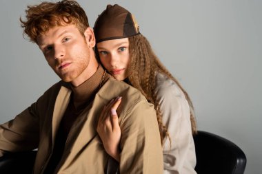 teenage girl with wavy hair hugging redhead boyfriend isolated on grey