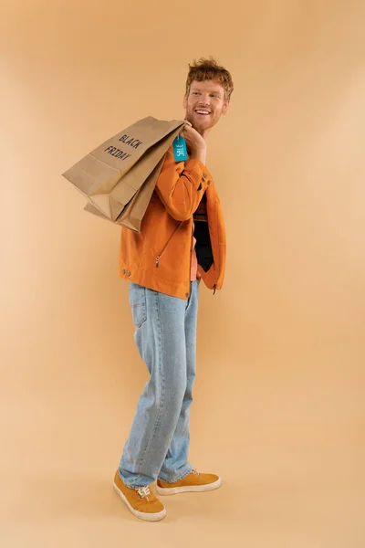 Cheerful Young Man Red Hair Holding Shopping Bags Black Friday — Stockfoto