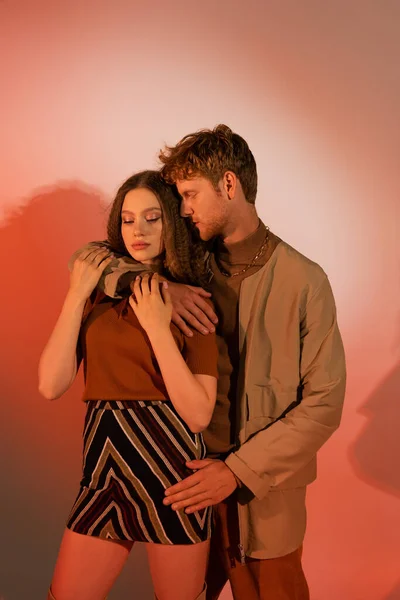 Young Man Hugging Stylish Girlfriend Skirt Red Background — Stock fotografie