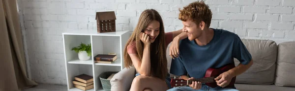 Curly Redhead Young Man Playing Ukulele Happy Girlfriend Living Room — Stock Photo, Image