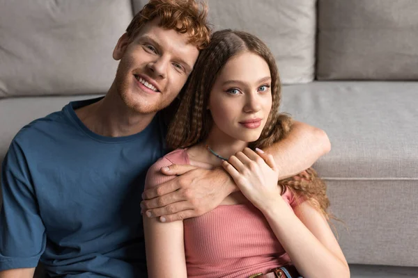 Redhead Young Man Smiling Hugging Pretty Girlfriend Living Room — Stok fotoğraf