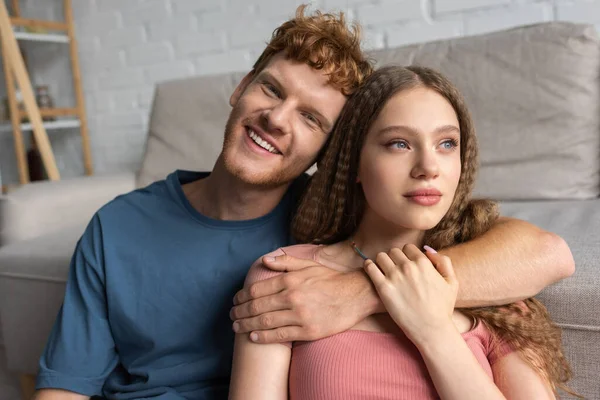 Redhead Happy Young Man Smiling Hugging Pretty Girlfriend Living Room — Stok fotoğraf