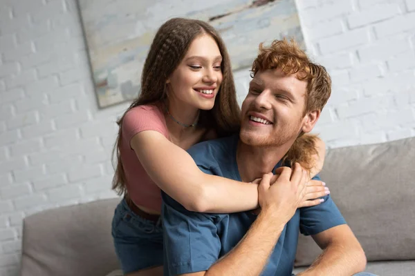 Cheerful Teen Girl Smiling Hugging Redhead Boyfriend Living Room — Stockfoto