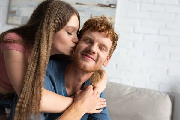 Pretty Teen Girl Hugging Kissing Cheek Redhead Boyfriend Living Room — Stok fotoğraf