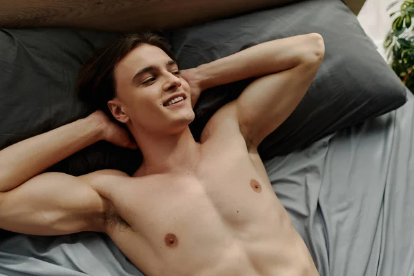 Top View Smiling Sexy Man Lying Black Pillows Hands Head — Stock Photo, Image