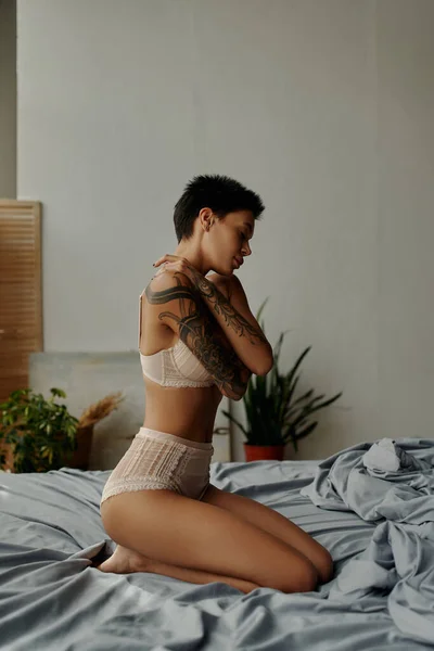 Vista Laterale Seducente Donna Tatuata Lingerie Che Abbraccia Mentre Seduta — Foto Stock