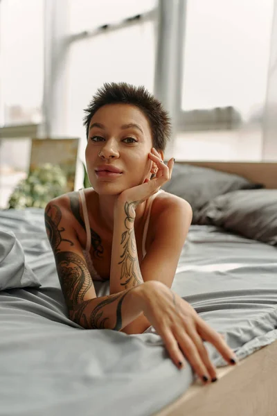 Sexy Tatuato Donna Guardando Fotocamera Mentre Sdraiato Sul Letto Mattino — Foto Stock