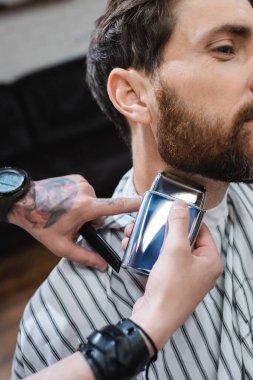 cropped view of barber shaving neck of bearded man with electric razor clipart