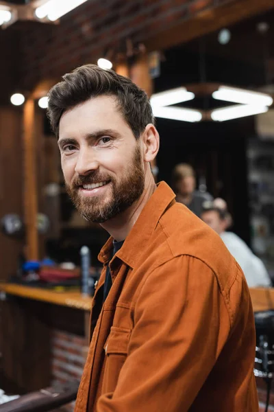 Brunette Man Beard Smiling Camera Blurred Barbershop — Stock Photo, Image