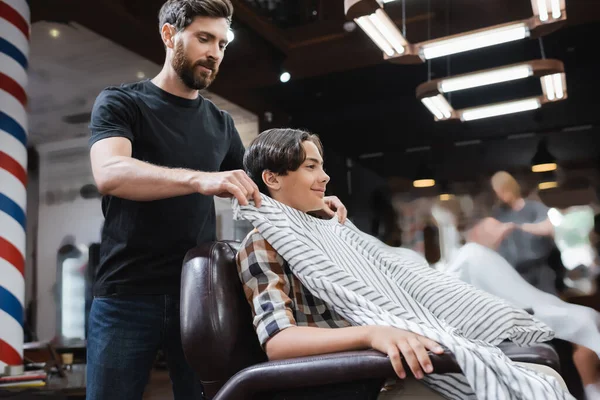 Barbero Barbudo Poniendo Capa Peluquería Cliente Adolescente Sonriendo Sillón — Foto de Stock